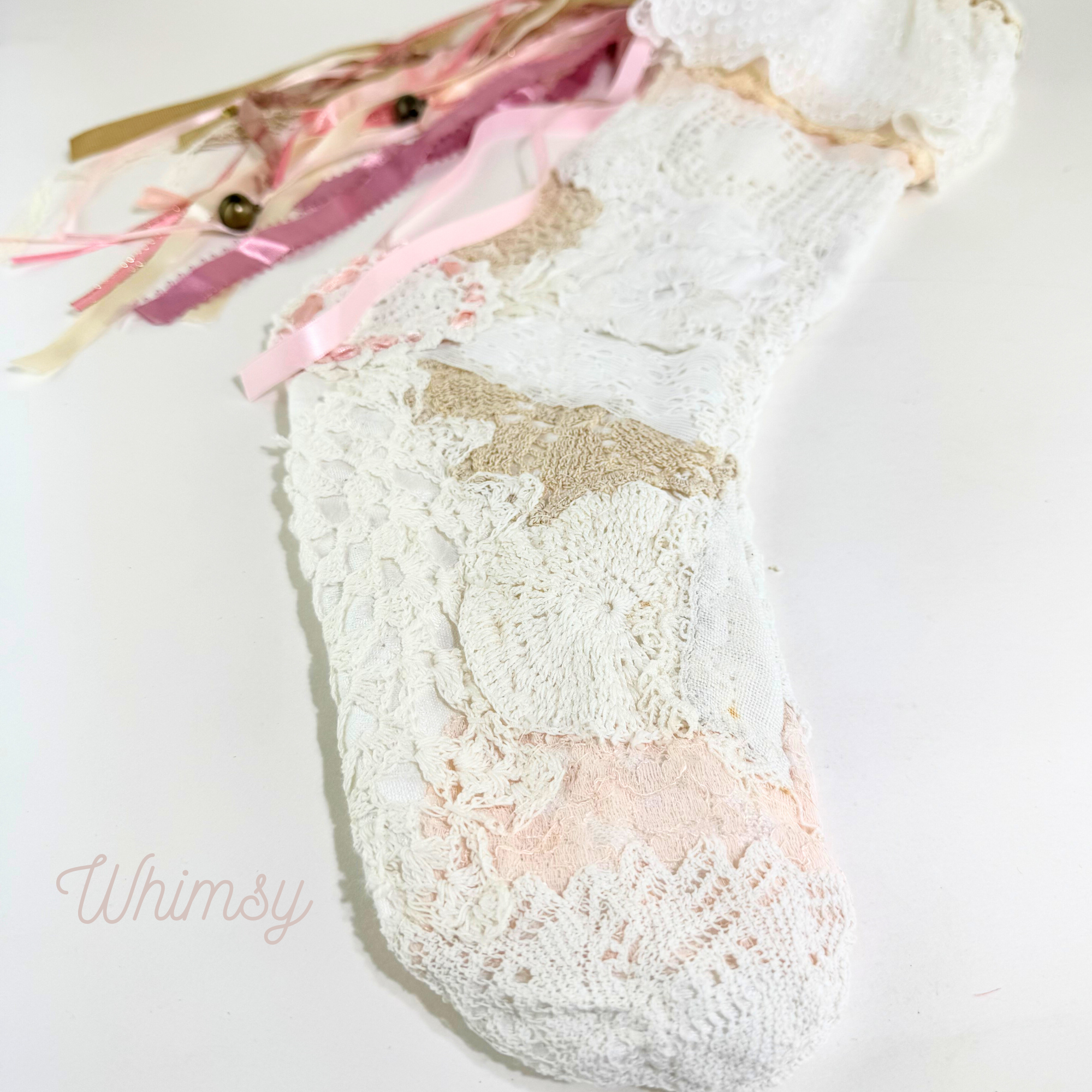 Flat lay of Whimsy handmade lace Christmas stocking with pink ribbons and delicate lace patchwork