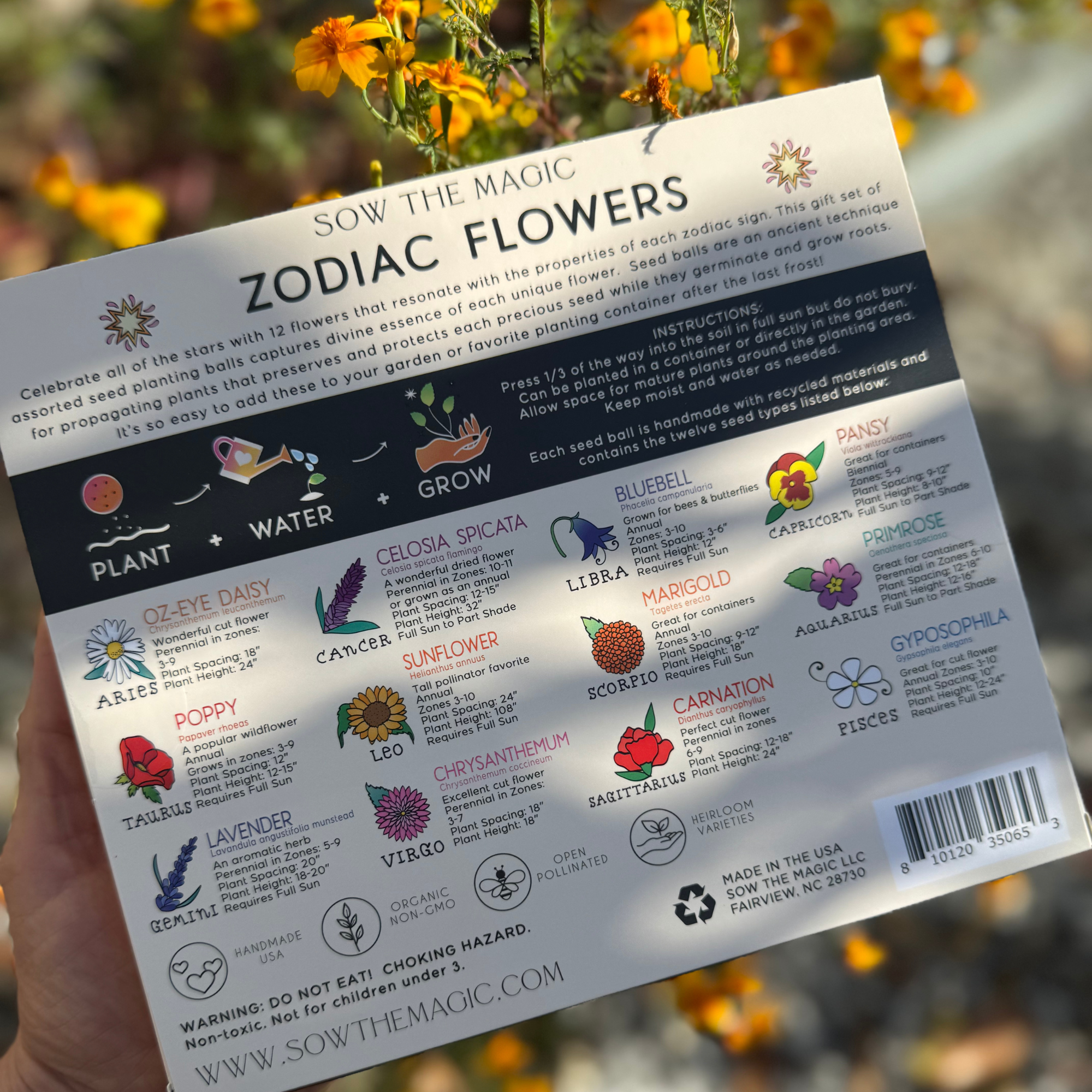 Back of Zodiac Flower Seed Ball box showing zodiac flower chart in sunlight among yellow flowers