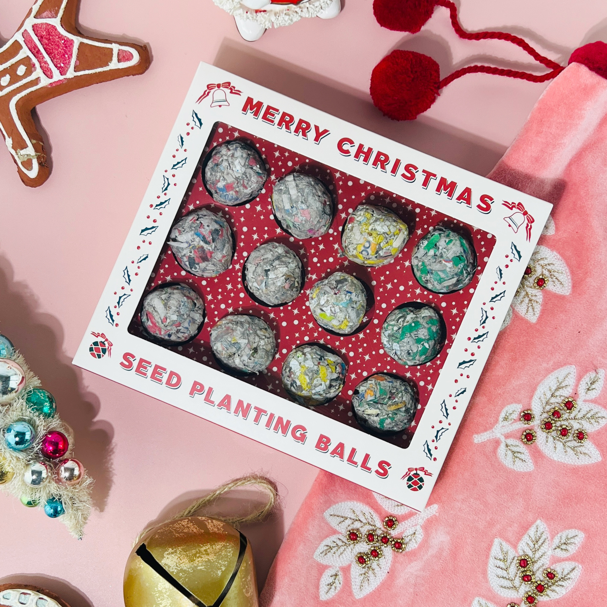 Festive holiday flatlay featuring 12 Days of Planting Christmas Seed Ball Set with ornaments and velvet stocking