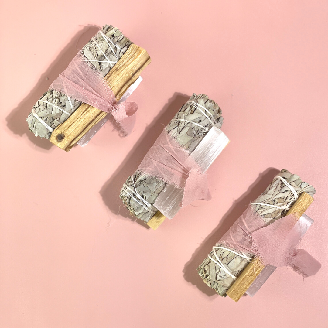 handcrafted White Sage Protection Ritual Bundles featuring White Sage, Palo Santo, a genuine Selenite cleansing wand and soft blush ribbon. Handmade spiritual gift sets by Sow the Magic®.