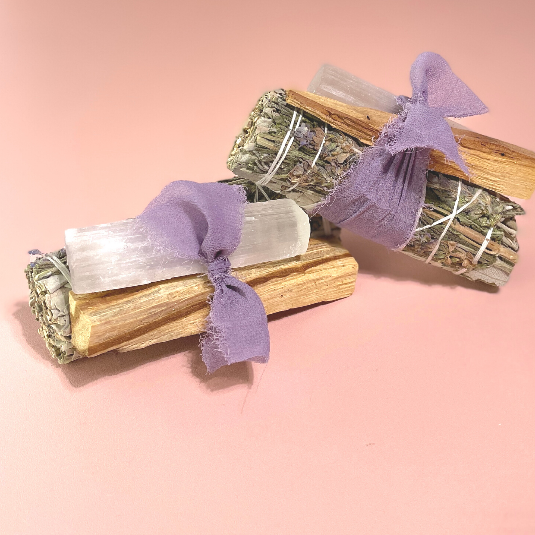 Handcrafted White Sage Protection Ritual Bundles featuring White Sage, a lavender smudge stick, genuine Selenite cleansing wand, Palo Santo stick and a soft lavender ribbon. Handmade spiritual cleansing gift set by Sow the Magic