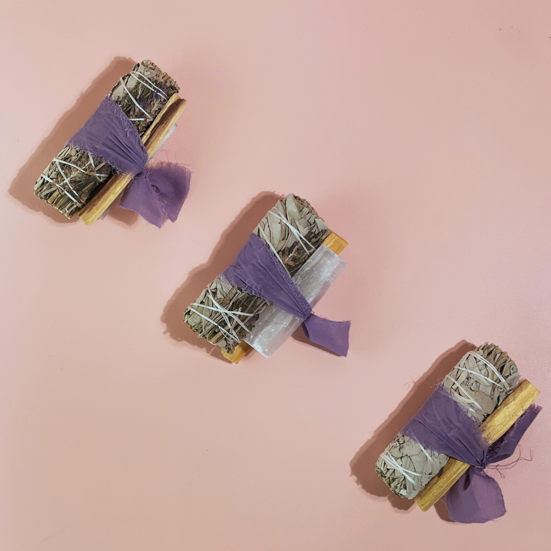 Handcrafted White Sage Protection Ritual Bundles featuring White Sage, a lavender smudge stick, genuine Selenite cleansing wand, Palo Santo stick and a soft lavender ribbon. Handmade spiritual cleansing gift set by Sow the Magic