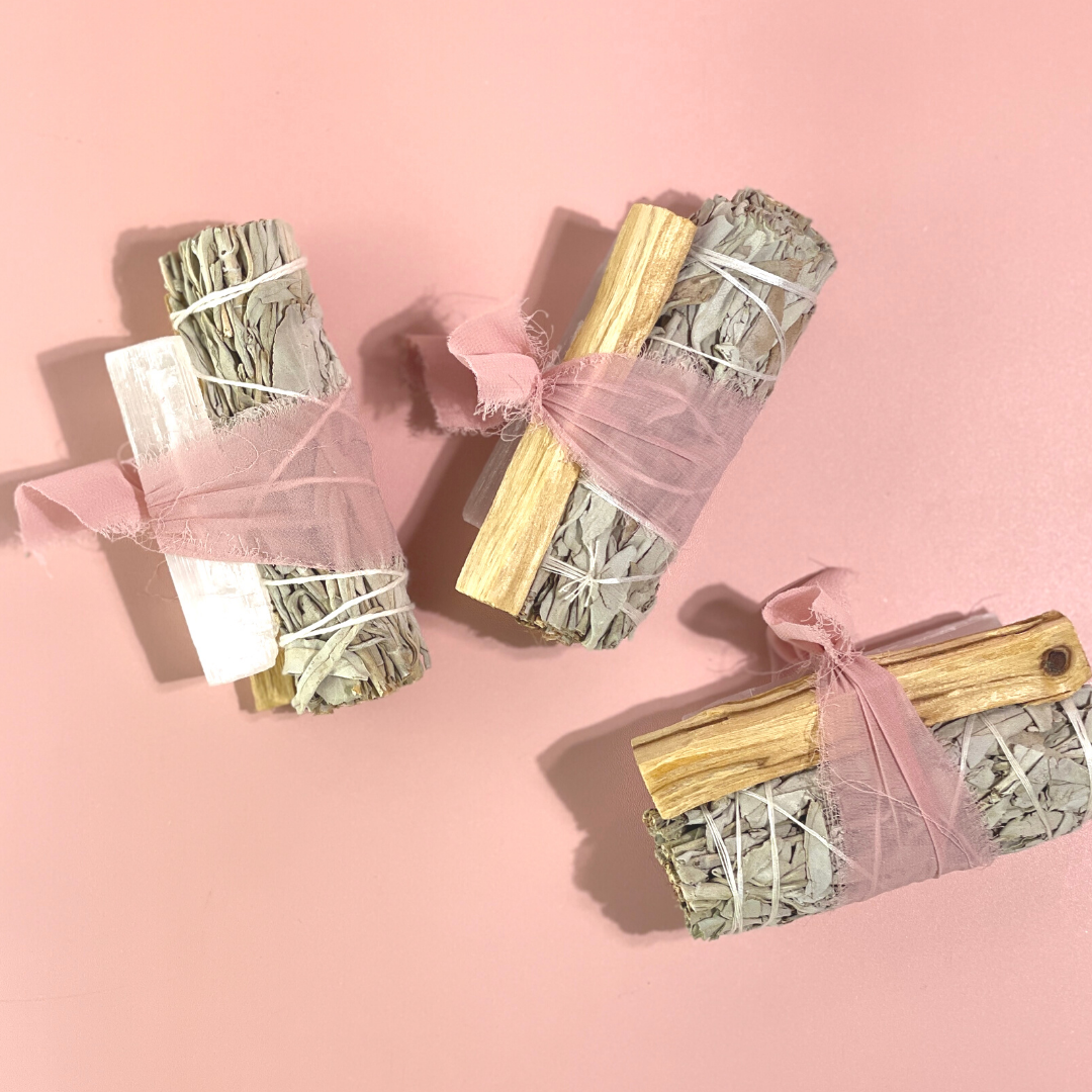 handcrafted White Sage Protection Ritual Bundles featuring White Sage, Palo Santo, a genuine Selenite cleansing wand and soft blush ribbon. Handmade spiritual gift sets by Sow the Magic®.