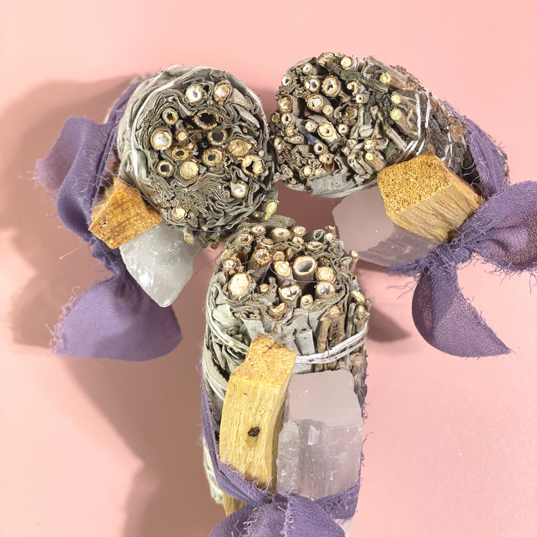 Handcrafted White Sage Protection Ritual Bundles featuring White Sage, a lavender smudge stick, genuine Selenite cleansing wand, Palo Santo stick and a soft lavender ribbon. Handmade spiritual cleansing gift set by Sow the Magic