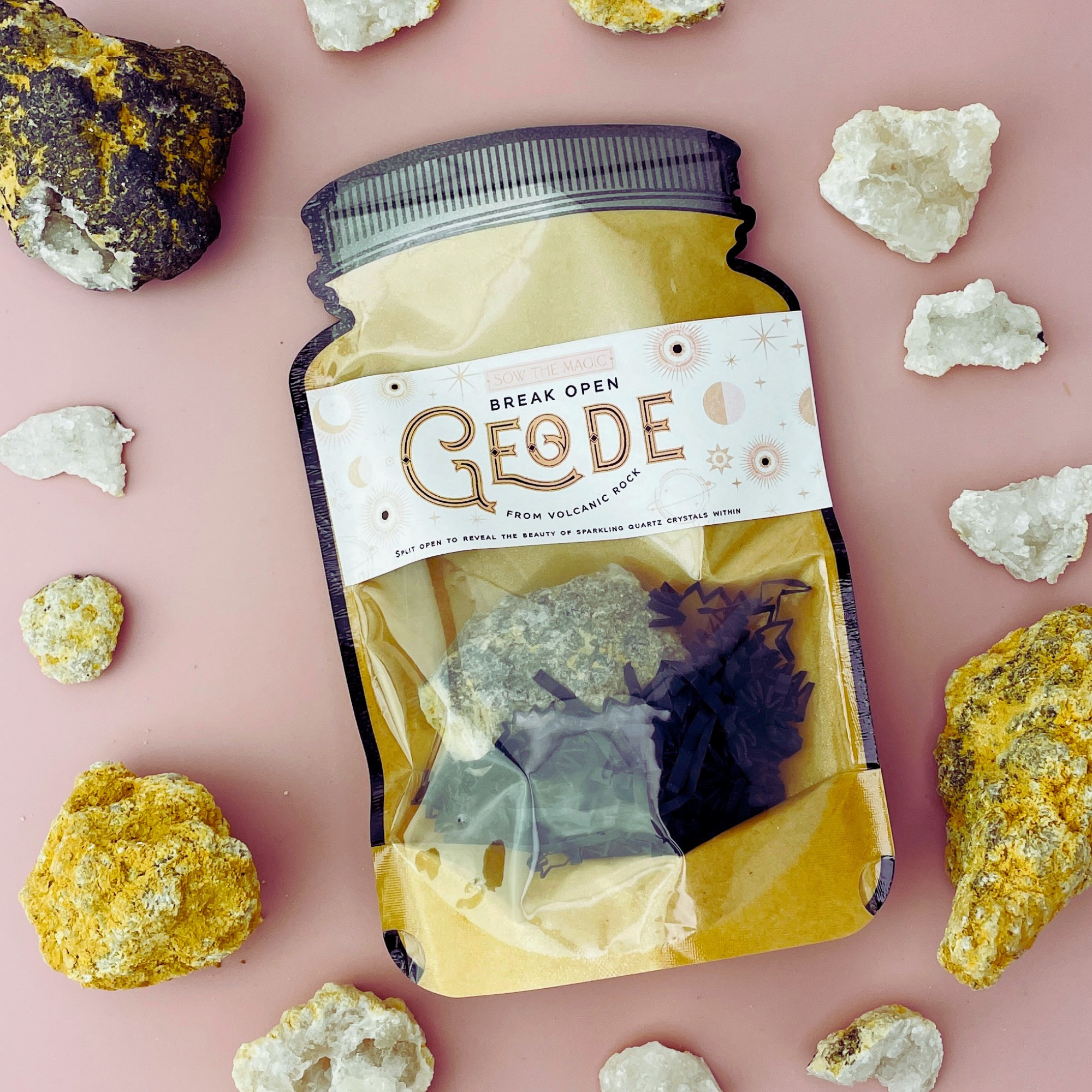 Break Open Geode Rock pouch surrounded by natural geodes and crystals on pink backdrop