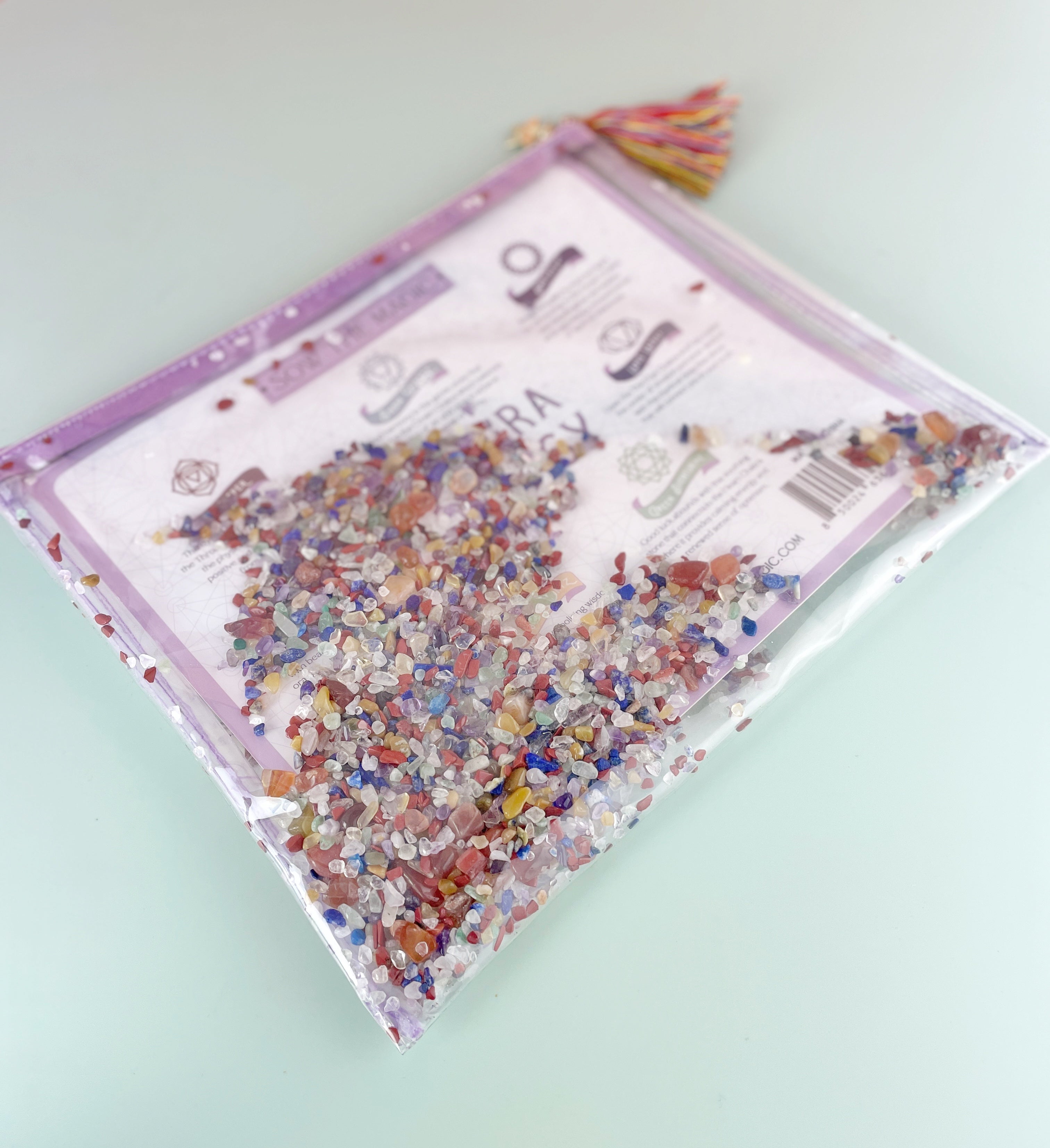Angled photo of Chakra Energy Gemstone Cosmetic Bag showing colorful crystal mix and purple zipper