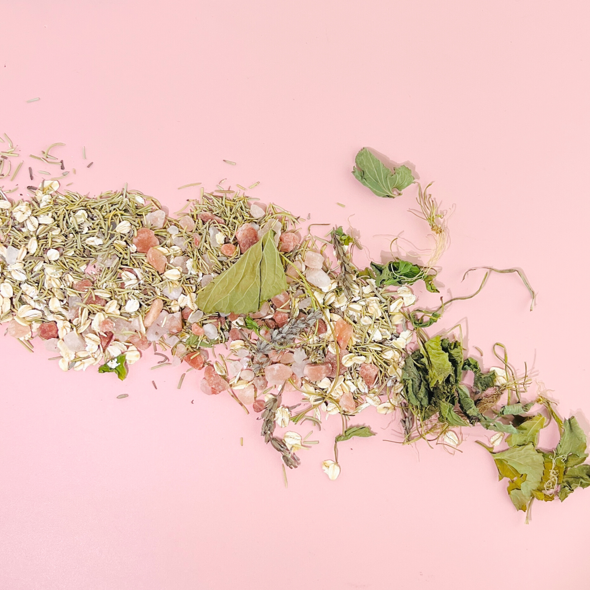 Close-up of Lavender Lovers Tarot Botanical Bath Tea loose blend with oats, Himalayan salt, herbs and lavender on pink background.
