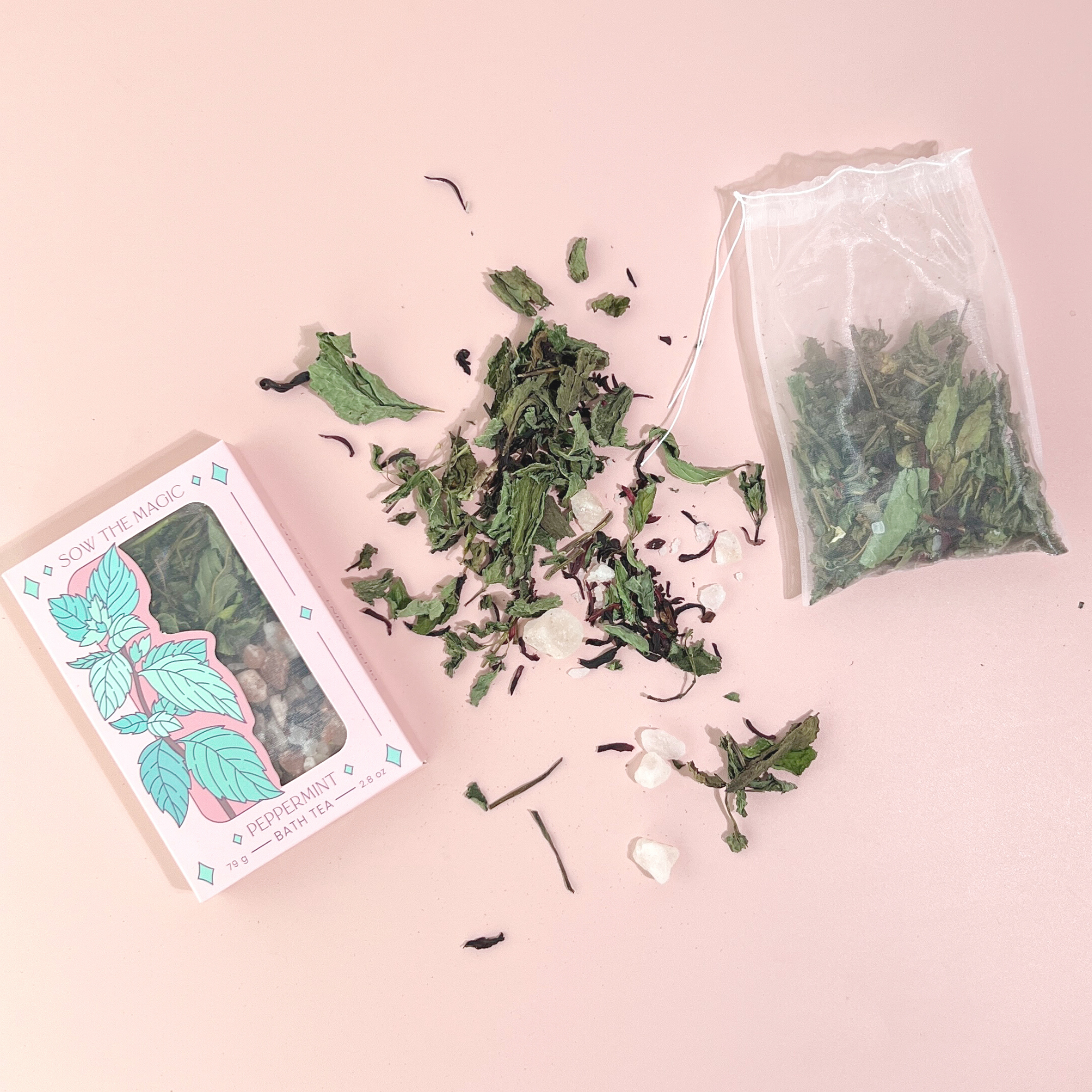 Peppermint Tarot Botanical Bath Tea Box next to loose herbal blend and filled tea bag on pale pink background.