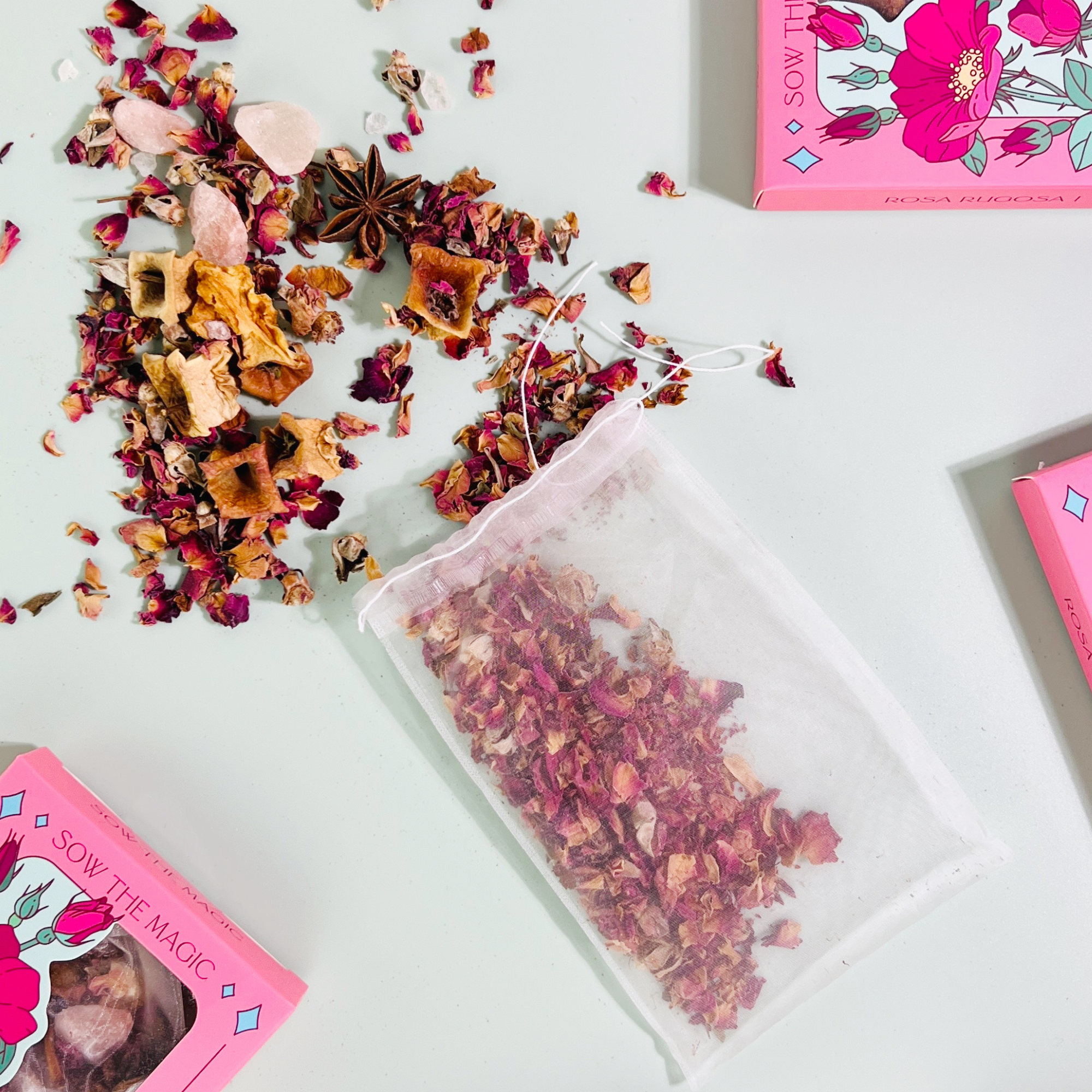 Rosa Rugosa Bath Tea by Sow the Magic with open reusable tea bag and dried rose botanicals scattered on light surface.